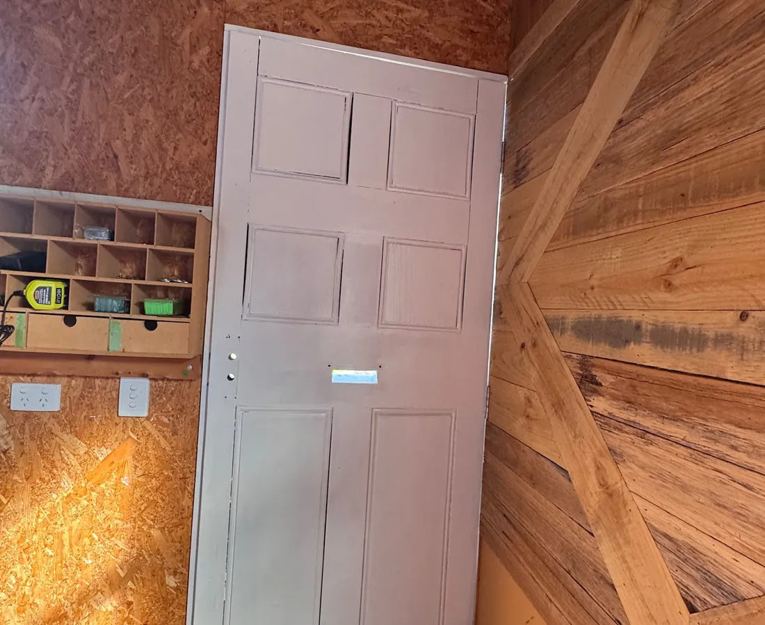Front door before painting, primed but unfinished, mounted in its frame