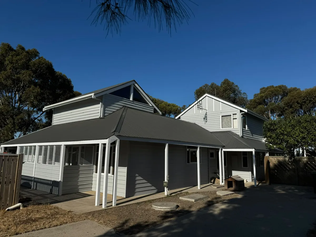 Two-storey weatherboard home with a freshly painted charcoal roofline and grey cladding