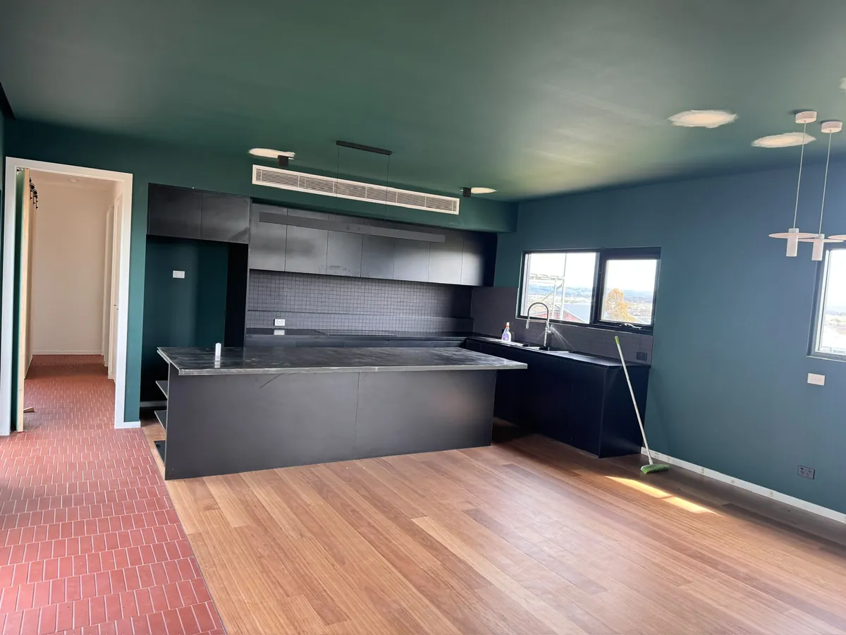 Kitchen finished in a deep teal ceiling and cabinetry colour with timber flooring